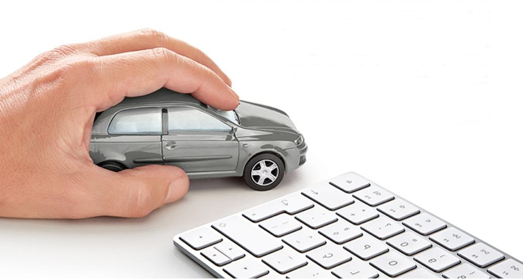 Mão a mover miniatura de automóvel próximo de um teclado